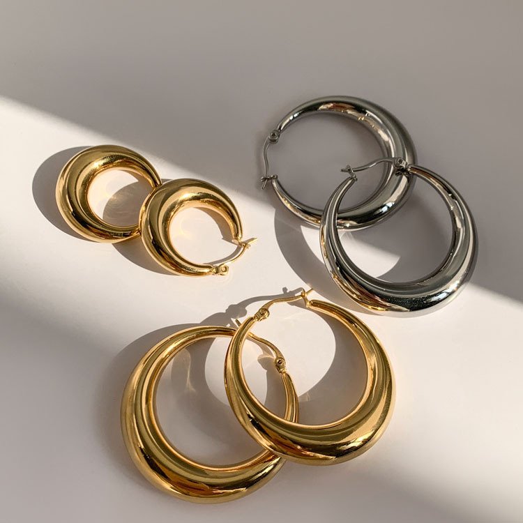 Metal round hoop earrings - elegant and simple, with a small and exclusive design touch. Luxurious and gold-colored accessory.